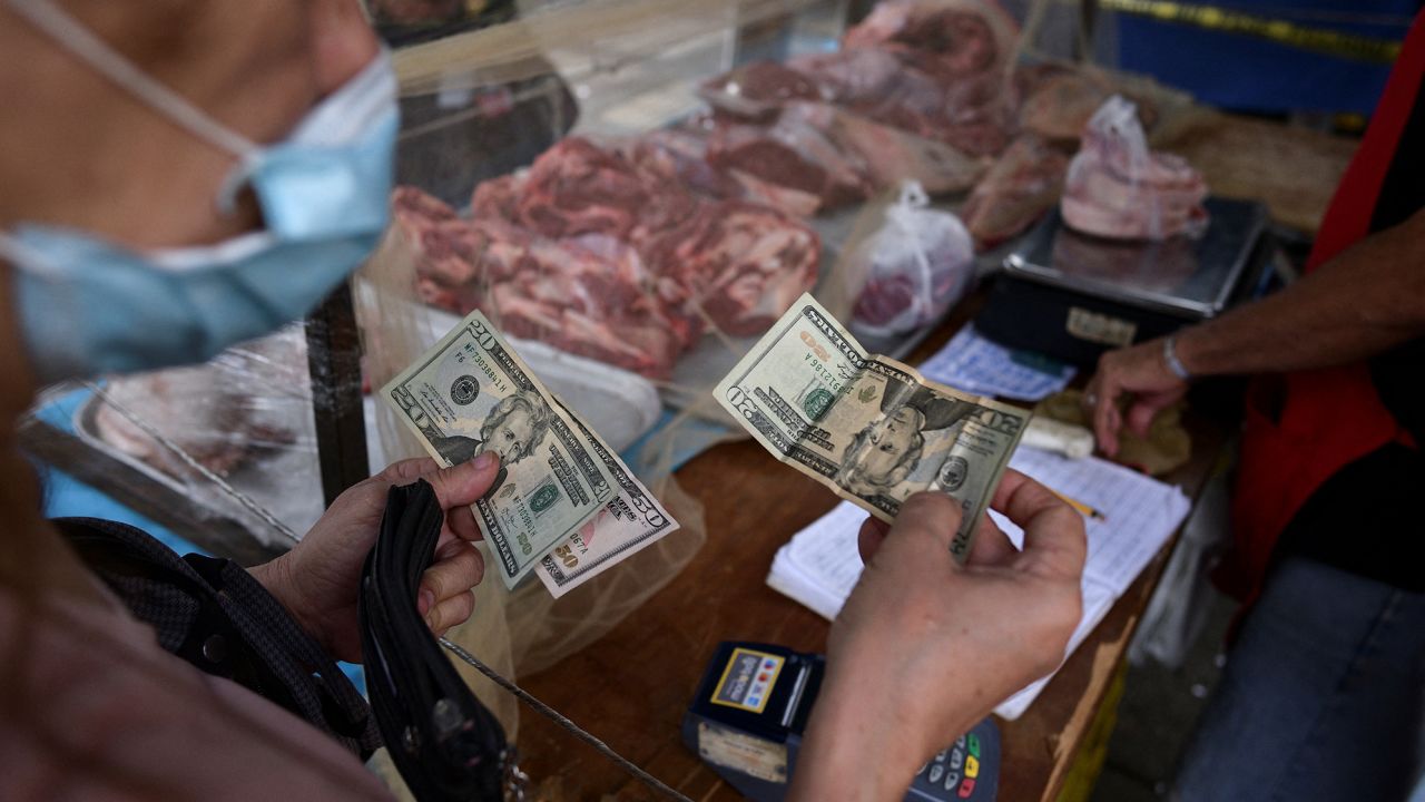 A customer pays for her purchase with U.S. dollar banknotes in an open-air fruit and vegetable market in Caracas, Venezuela February 10, 2023.